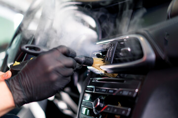 Fototapeta na wymiar A car wash worker carefully cleans the interior of a luxury car with a rag a brush a vacuum cleaner a steamer detailing 