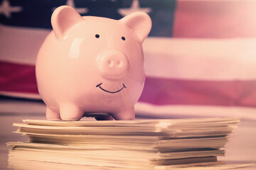 Close up pink piggy bank on United States Dollar bills as symbol of wealth and power.