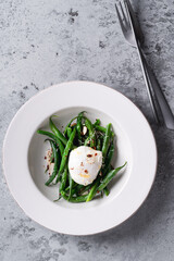 Sauteed green beans with almond nuts, salt, pepper and poached egg, healthy salad for breakfast