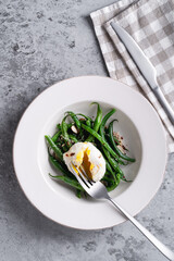 Sauteed green beans with almond nuts, salt, pepper and poached egg, healthy salad for breakfast