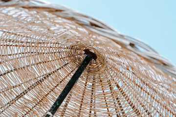 Summer texture and background. Wicker lattice roof of a beach umbrella against blue sky. Holidays...