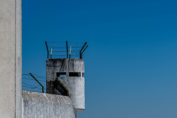 Old prison watchtower topped with barbed wire fencing