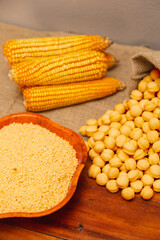 Corn cobs, corn flakes and corn snacks, bagged on a wooden background, generated with an extruder machine