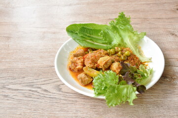spicy fried pork bone with curry and basil leaf with fresh vegetable on plate 