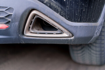 Automotive exhaust pipe or tailpipe tip Standing nondescript car close-up view from a low angle in...