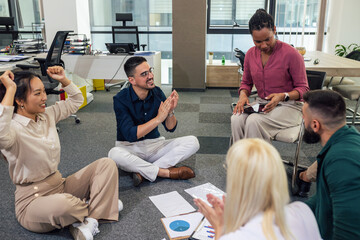 A group of professional people sitting on the floor of the office and working together