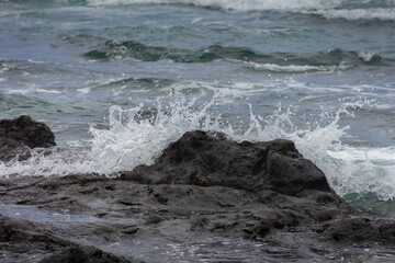 water from the ocean splashing over a rock