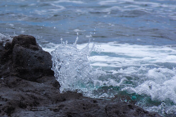 water from the ocean splashing over a rock