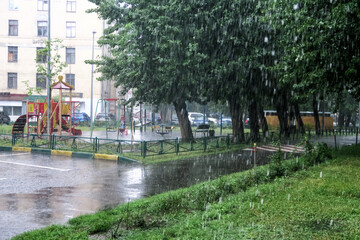 Heavy rain in the Park. Puddles on the sidewalk. Heavy raindrops fall into a puddle on the...