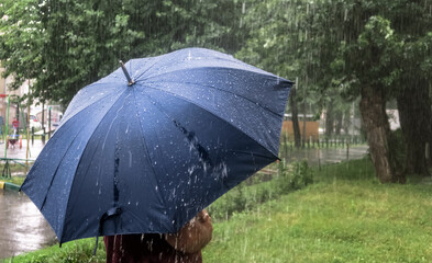 Heavy rain in the Park. Puddles on the sidewalk. Heavy raindrops fall into a puddle on the...