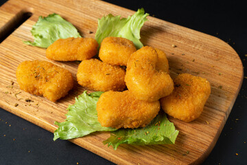 Naklejka premium Chicken nuggets laid out on a board with lettuce and mushrooms