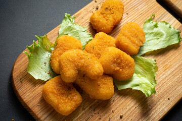 Chicken nuggets laid out on a board with lettuce and mushrooms