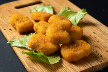 Chicken nuggets laid out on a board with lettuce and mushrooms