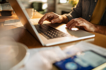 young man using a laptop while working from home and going over his bills and home finances