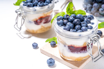 

Layered blueberry parfait dessert, cheesecake in glass with vanilla biscuit, creamy yogurt, jam topping and fresh blueberry
