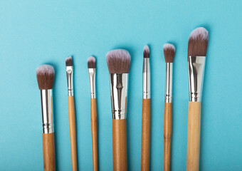 Cosmetic makeup brush on a blue background. Cosmetic product for make-up. Creative and beauty fashion concept. Fashion. Collection of cosmetic makeup brushes, top view, banner.Place for text. 