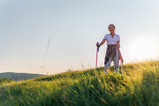 a young adventurer uses walking sticks as she walks through the fields