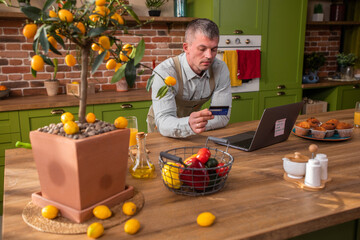 In the morning at the kitchen beautiful couple speeding time together the man wants to order something online beautiful woman hugging with love and smiling