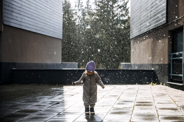 Child walking under the rain on a spring day.