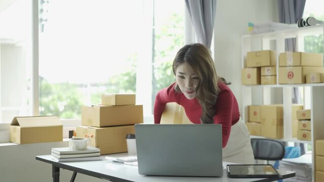 Happy successful asian businesswoman excited to receive purchase order and check stock Working at home office with parcel box laptop small business owner Online marketing, SME business concept