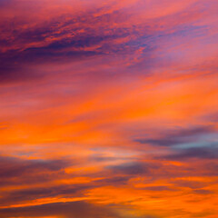 Vibrant orange red colours of sunset sky with clouds. Dramatic sky, light majestic sunset