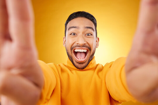 Funny, portrait and selfie of excited man in studio isolated on a yellow background. Face, smile and Asian person taking profile picture for happy memory, laughing and photography on social media