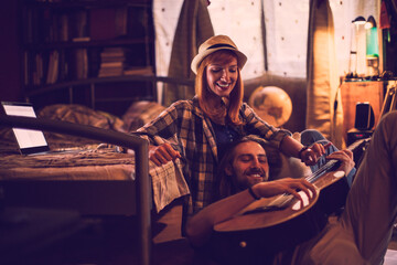 Young couple playing the guitar and singing in the bedroom together