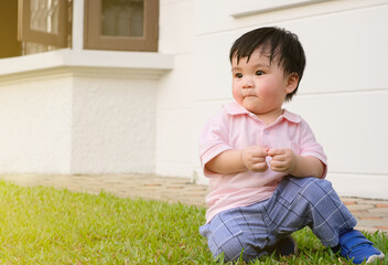 Close up portrait of asian baby sweating on face playing in the home garden. Joyful and healthy...