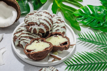 Profiteroles choux pastry buns with coconut cream served in tropical style. Palm leaves