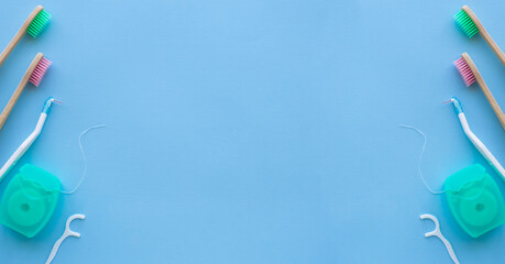 Dental concept background with copy space for text. Close up view of photo with dental floss, floss stick and wooden toothbrush on blue background. Medical card for design. 