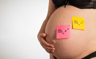 Stickers on the belly of a pregnant girl with inscriptions negative and positive Rh factor. Rh...