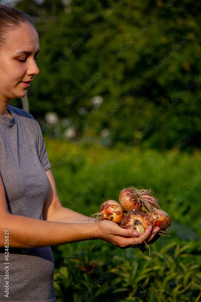 Poster the farmer girl holds an onion in her hands. Selective focus.