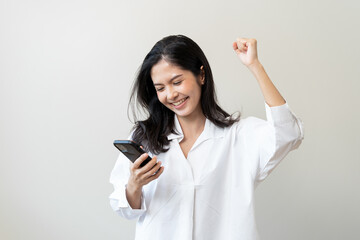 Fototapeta premium Happy Asian woman holding a smartphone and winning the prize.
