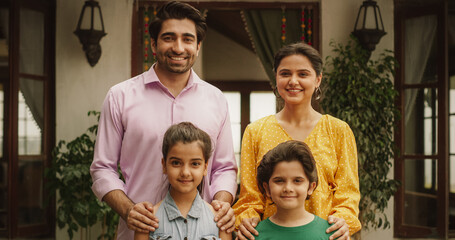 Portrait of Happy Indian Nuclear Family Posing Together Under Natural Light. Gorgeous Parents and Their Cute Two Kids Looking at the Camera, Happy in Their Newly Purchased Home