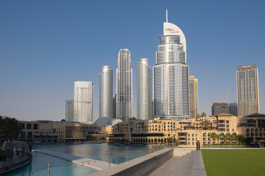 Dubai UAE Jun 17 2023: City skyline of many Emaar Properties highrise residential condo and business buildings by the fountain on Burj Khalifa Lake in front of Dubai Mall in city downtown.