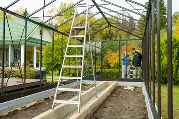 Senior couple working on a project in their garden. Man and woman constructing a greenhouse in their backyard.