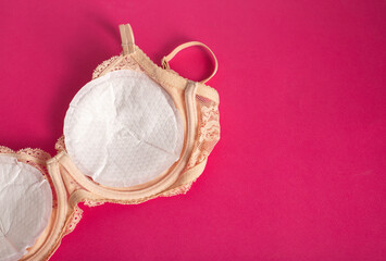Women's bra with liners against the flow of milk from the breast of a nursing woman on a pink...