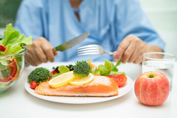 Asian elderly woman patient eating salmon steak breakfast with vegetable healthy food in hospital.