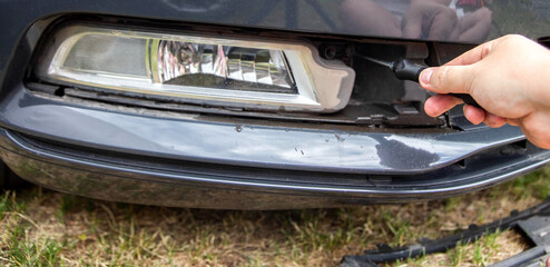 Unscrewing and disassembling the fog lamp in a car to replace the light bulb with a new one, close-up