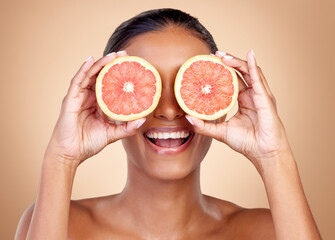 Grapefruit, beauty and eyes of happy woman in studio, vitamin c nutrition or natural glow. Face of female model, healthy skincare or smile with citrus fruits, eco dermatology or sustainable cosmetics