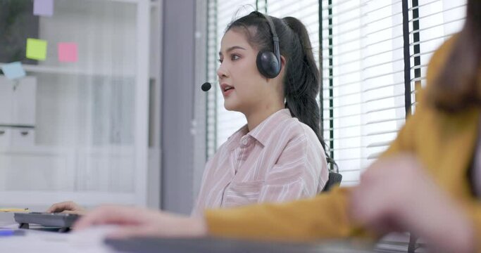 two female call center worker is consulting with a customer who calls in for information over the phone in the office. Businessman wearing headphones to talk to customers. communication technology