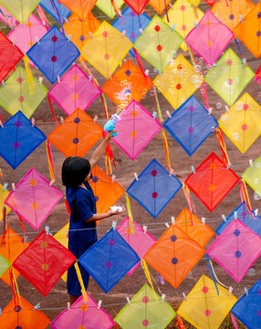 Vertical image of Asian girl enjoy to play bubble gun alone in area of row of kites outdoor and day light.