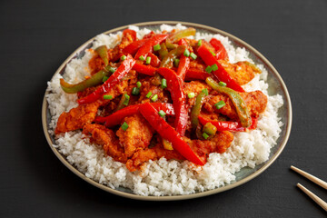 Homemade Simple Chili Chicken with White Rice on a Plate on a black background, side view.