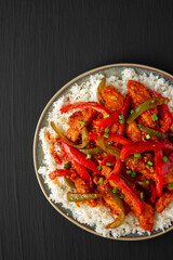 Homemade Simple Chili Chicken with White Rice on a Plate on a black background, top view. Flat lay, overhead, from above. Space for text.
