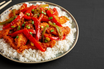 Homemade Simple Chili Chicken with White Rice on a Plate on a black background, side view.