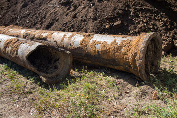Replacement city water supply, old rusty pipes among heaps of earth.