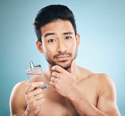 Portrait, cosmetics and man with cologne, beauty or self care against a blue studio background....