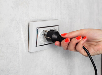 The girl removes the electrical plug from the socket and breaks the socket out of the socket....
