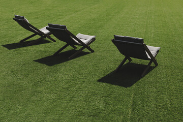Three lounge chairs stand on the grass on a sunny day 