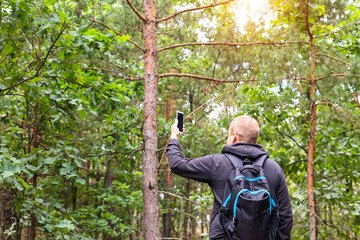 A man holds a smartphone in his hand on the background of the forest. The concept of poor cellular...